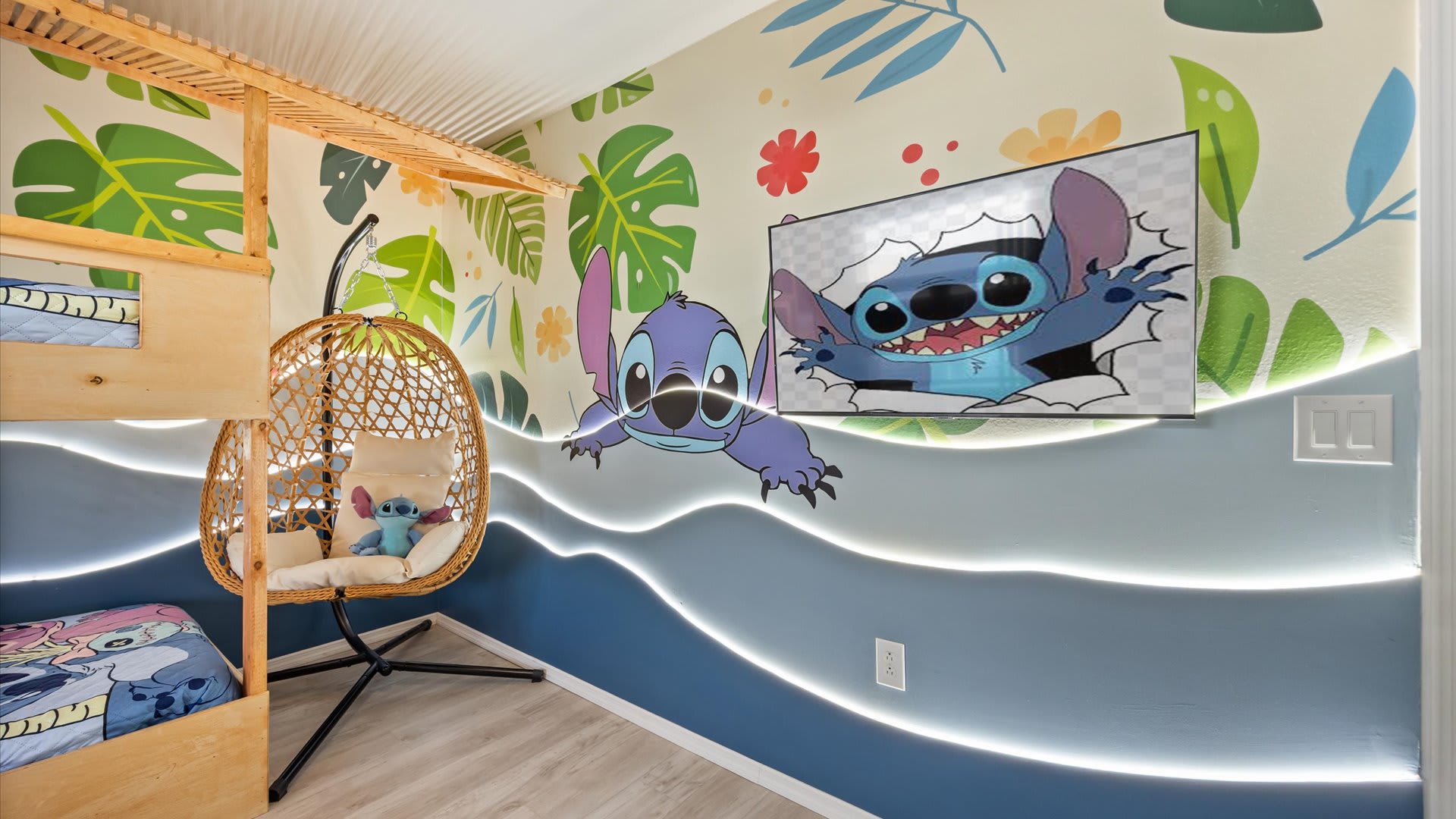 A playful Stitch-themed bedroom with a tropical leaf mural and wave-patterned walls featuring integrated LED lighting, a unique hanging egg chair, and a wall-mounted TV displaying Stitch.