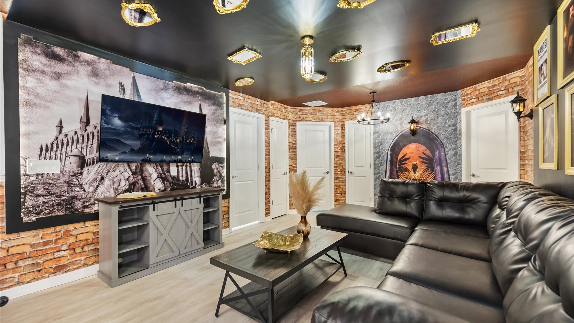 Harry Potter-themed media room with a large flat-screen TV mounted on a Hogwarts mural, a dark leather sectional sofa, and brick-patterned walls with framed wizarding world art.