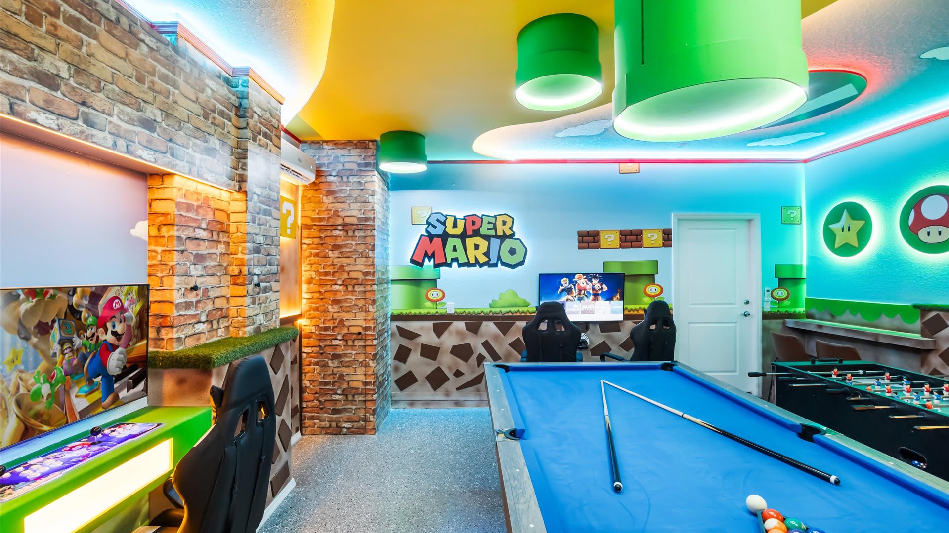 Another view of the Super Mario-themed game room, highlighting the arcade machines, gaming chairs, and the vibrant blue and green walls with character cutouts and LED strip lighting.