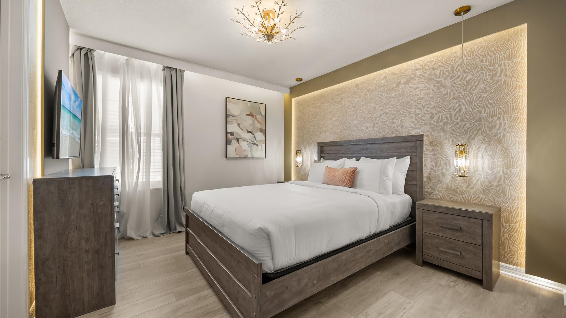A stylish bedroom featuring a queen-sized bed with a grey wooden frame, light wood flooring, and a textured accent wall with warm backlighting behind the bed.
