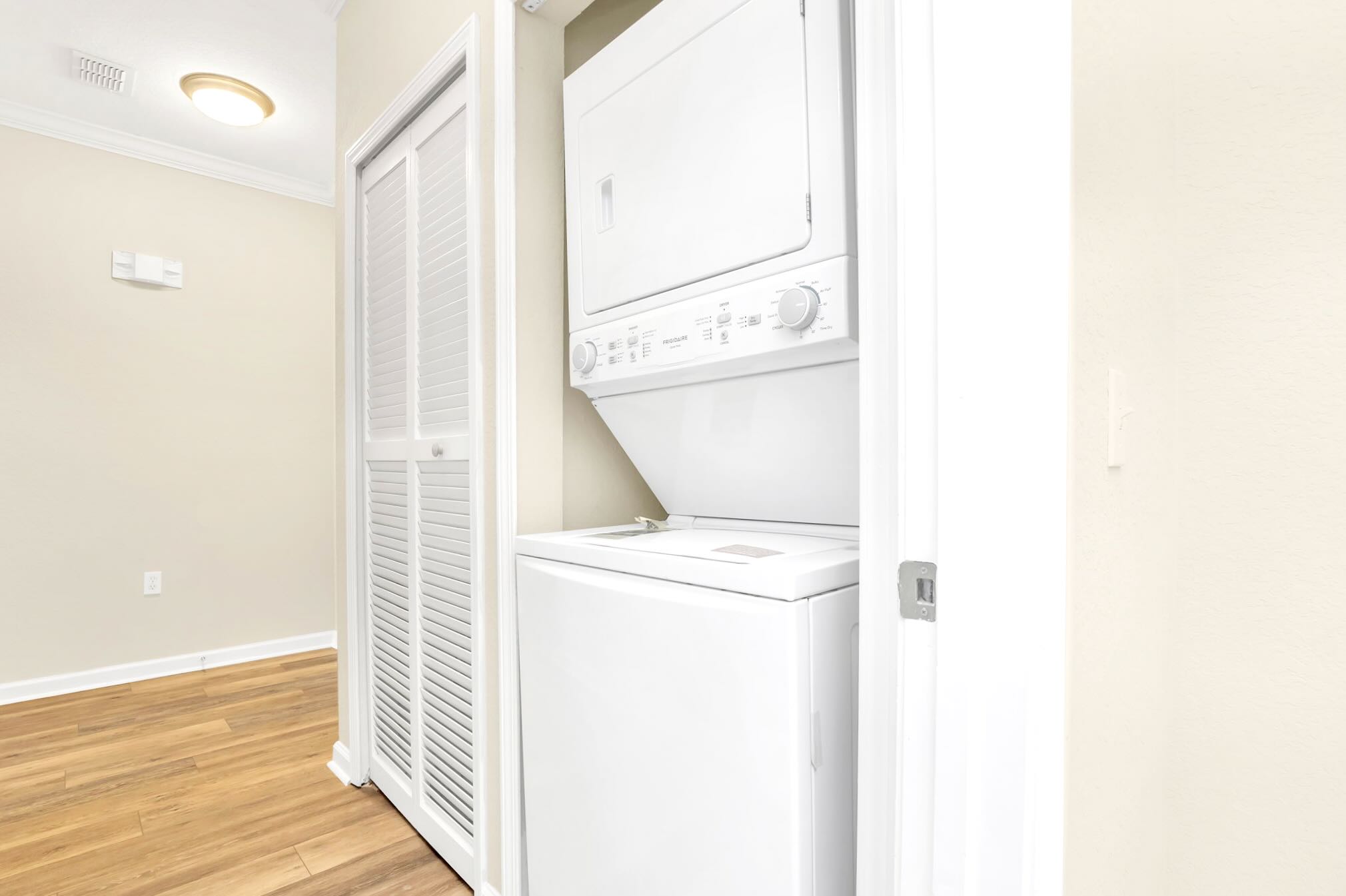 A dedicated laundry closet houses a white stacked washer and dryer unit, providing in-unit laundry facilities for guests.