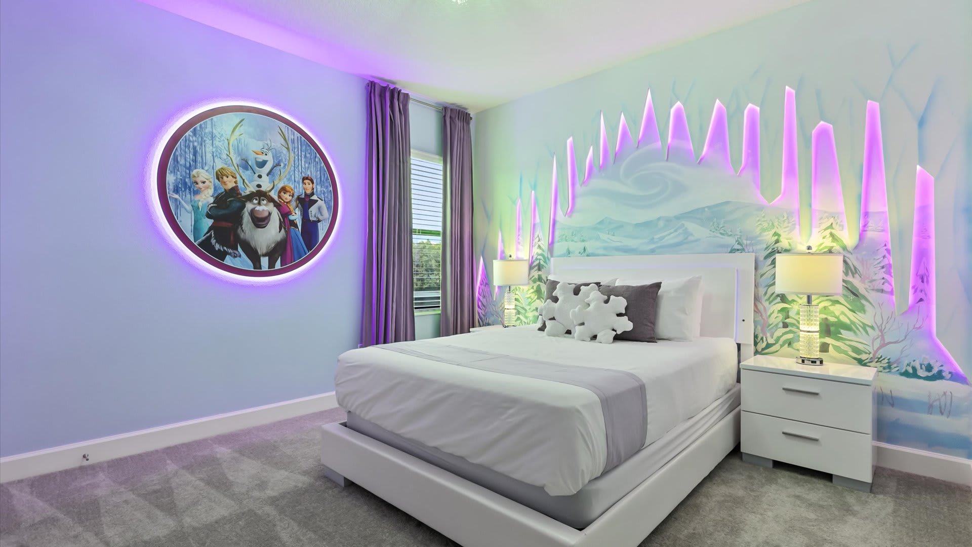 A 'Frozen' themed bedroom with light purple walls, a white queen-sized bed, and illuminated ice-like wall art. A large circular illuminated artwork featuring 'Frozen' characters is prominently displayed on the left wall.