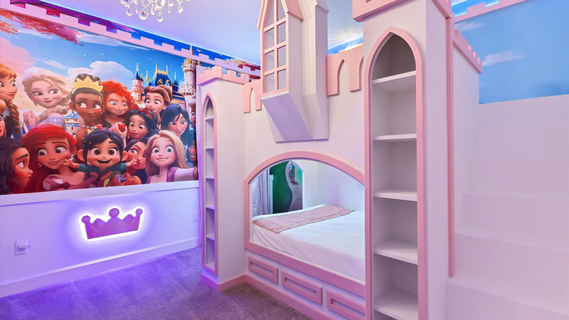 Enchanting Princess themed bedroom featuring a pink and white castle-shaped bunk bed, a large wall mural of Disney princesses, and a glowing crown wall decor. The room is softly lit with pink and purple hues.