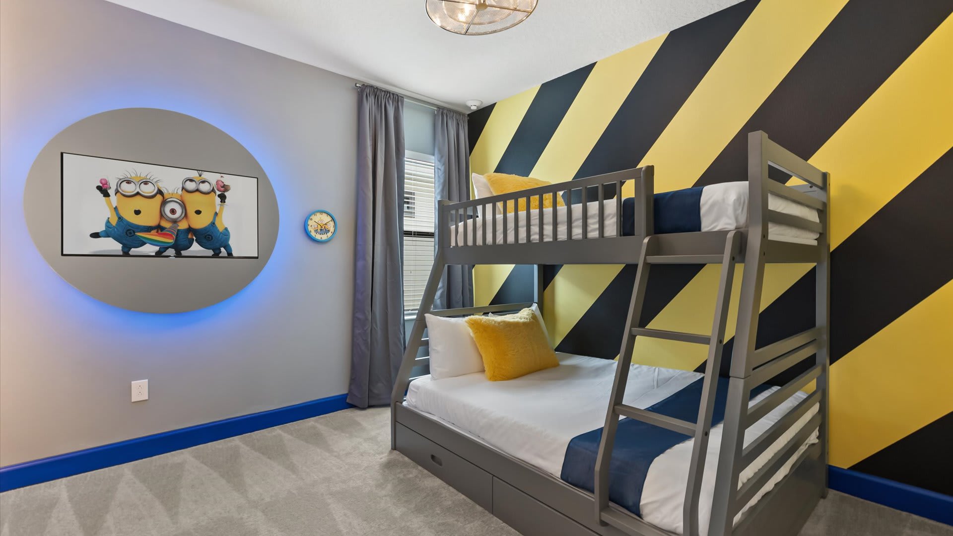 A 'Minions' themed bedroom features a grey bunk bed and a striking yellow and black striped accent wall. A circular wall-mounted TV with blue backlighting displays Minions characters.