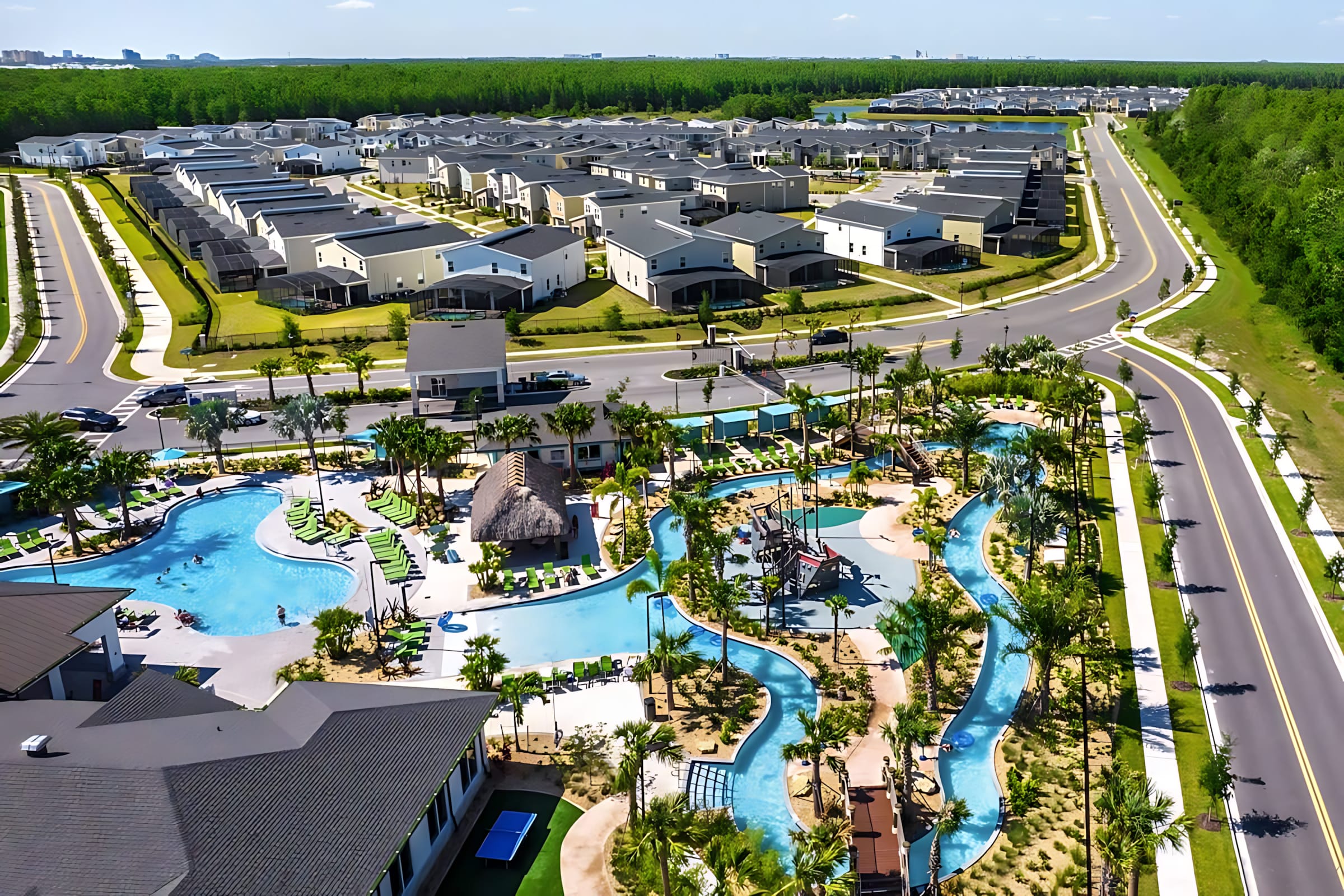 Aerial view of a large resort community featuring a sprawling communal pool complex with a lazy river, water features, and numerous vacation homes surrounded by lush greenery.
