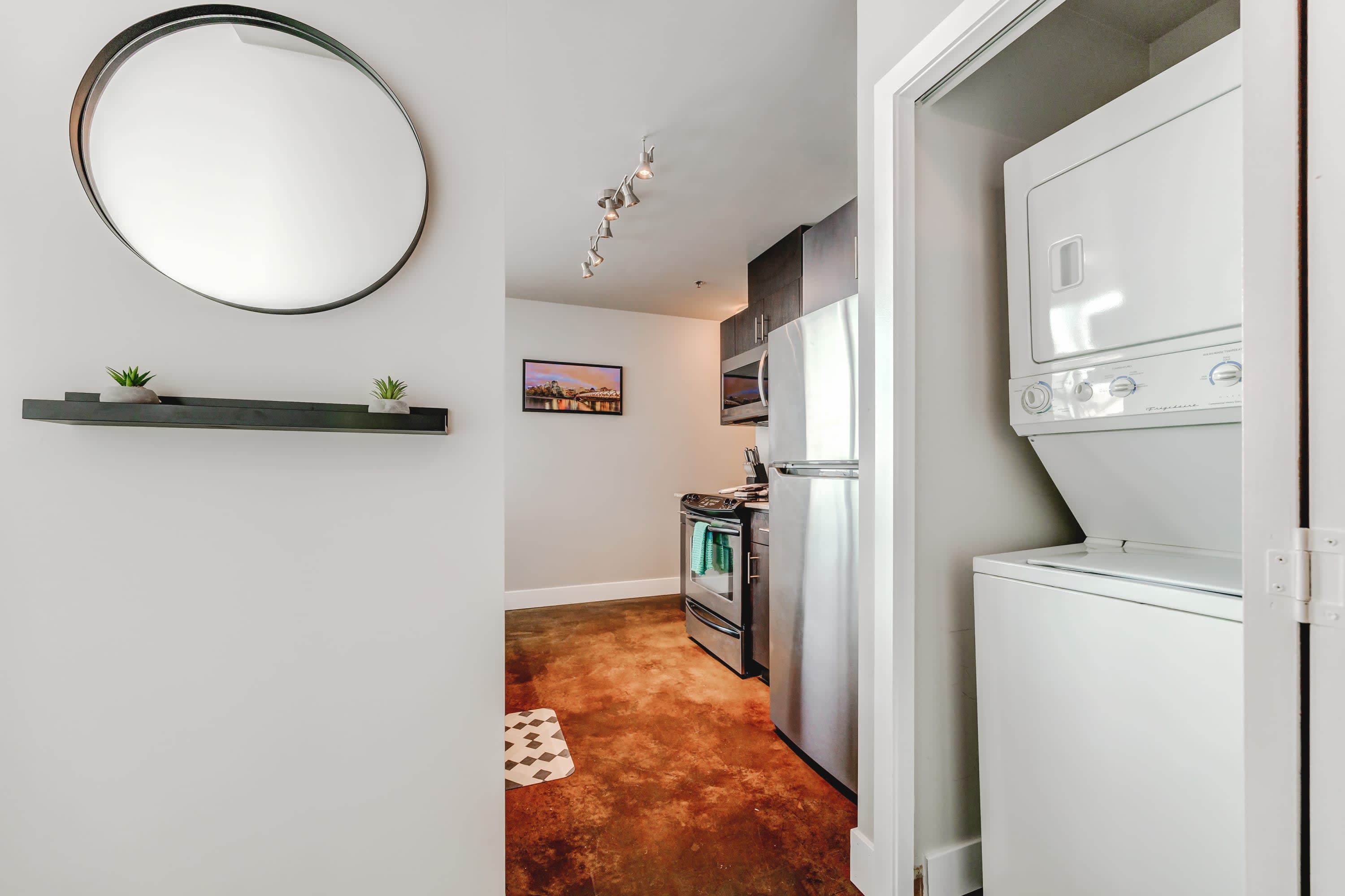 Compact laundry area featuring a stacked white washer and dryer unit neatly tucked into a closet, conveniently located near the kitchen entrance.