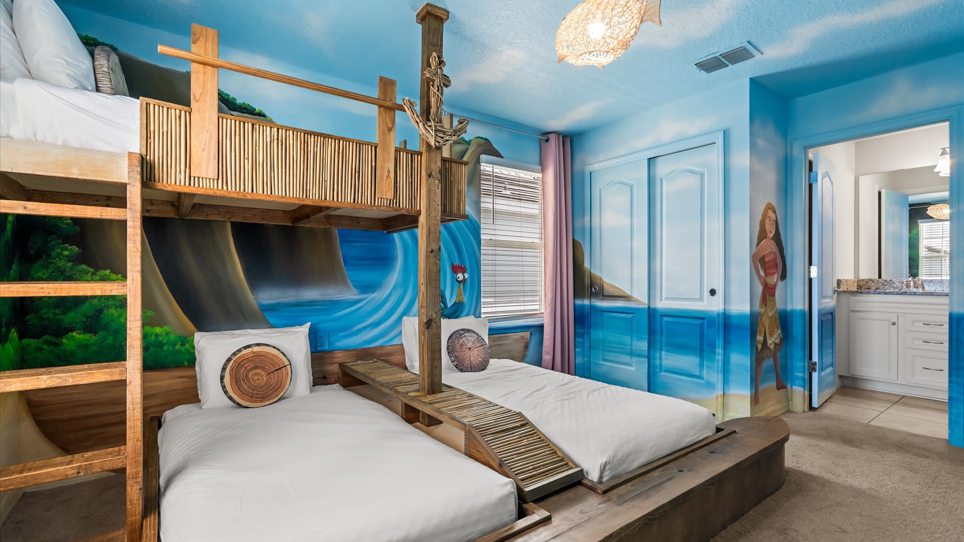 A comprehensive view of the Moana-themed bedroom with custom wooden bunk beds, vibrant wall murals, and an open doorway leading to an en-suite bathroom with a double vanity.
