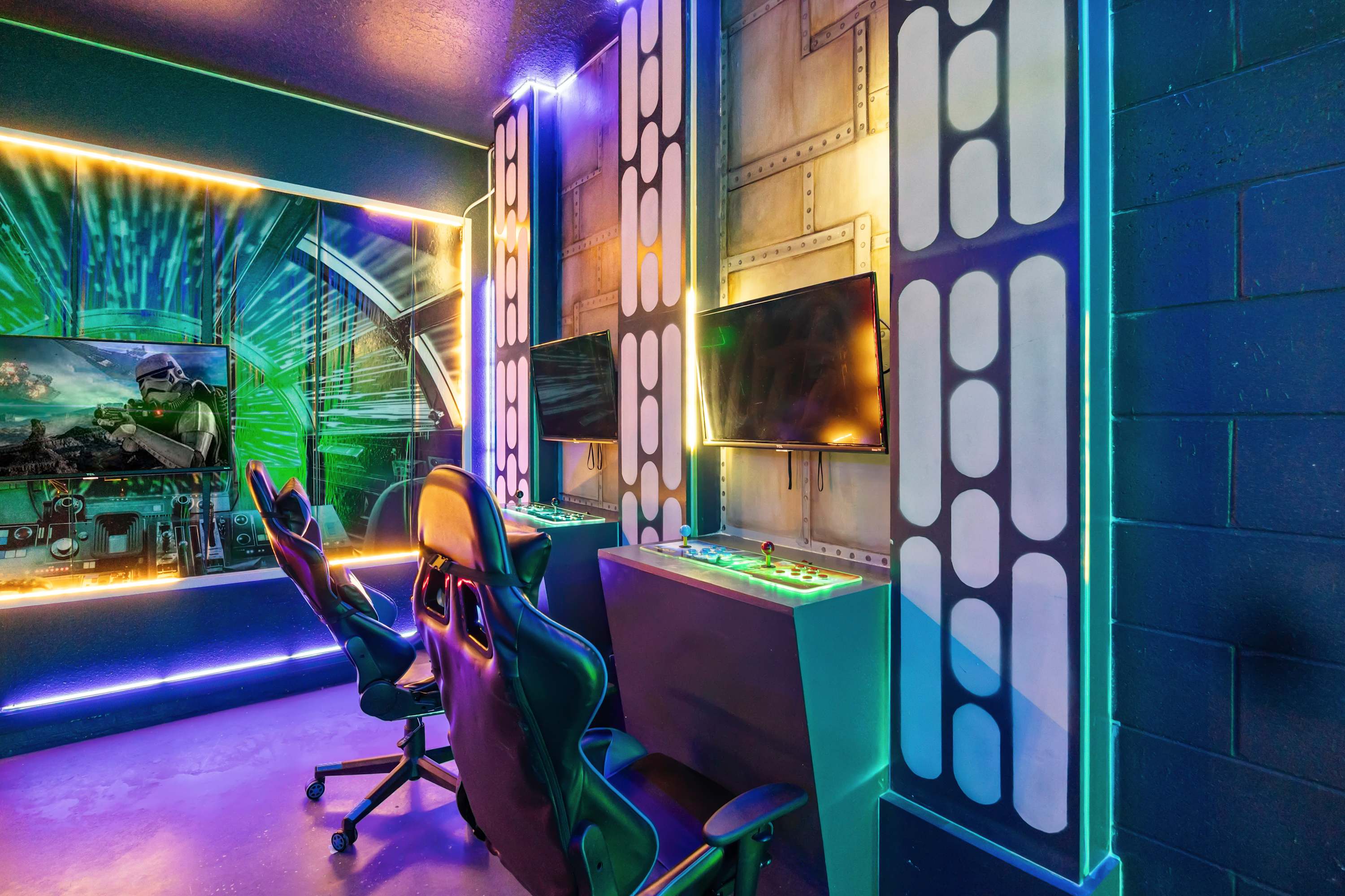 Star Wars-themed game room with two gaming stations, each featuring a monitor and arcade controls, set against dark walls with neon strip lighting and themed wall panels.