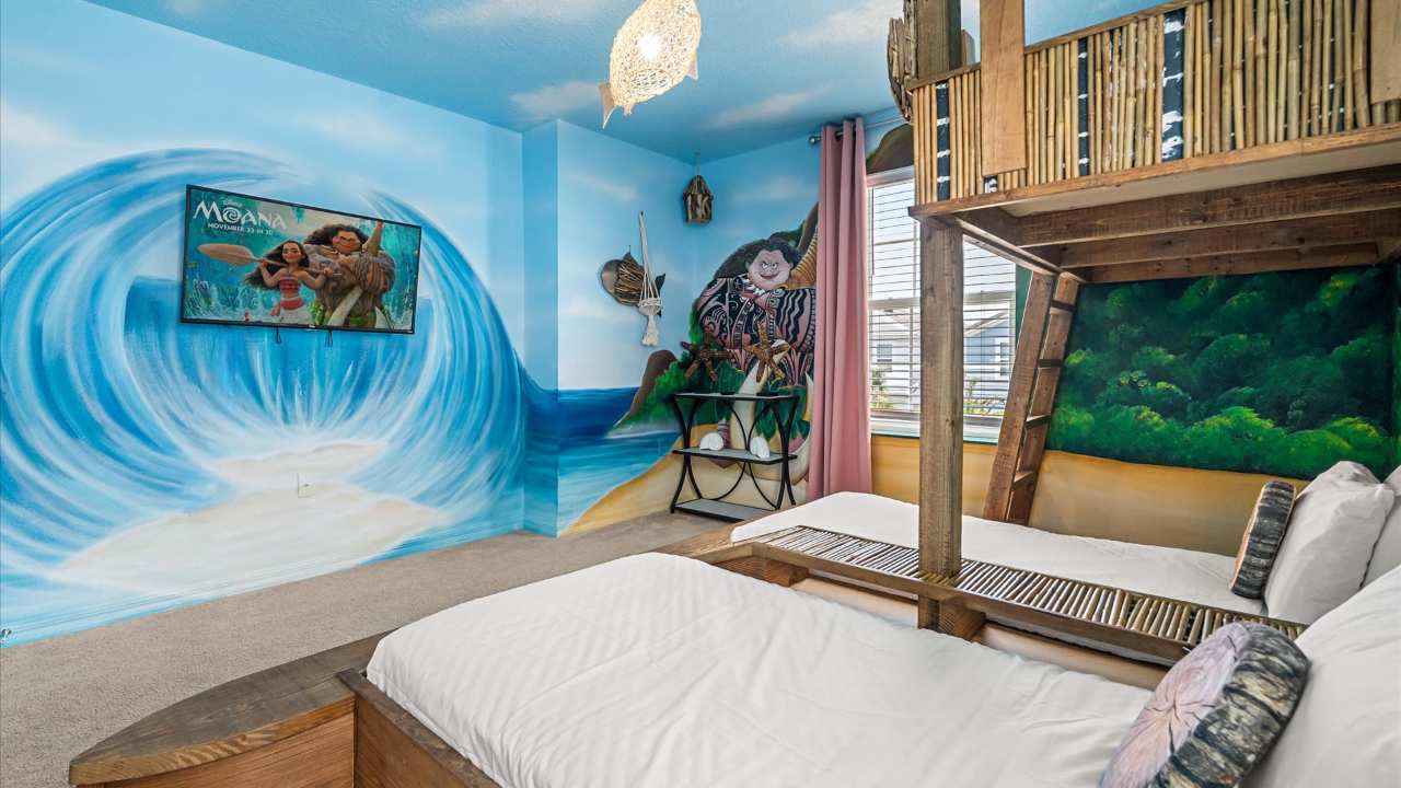 A wide view of the Moana-themed bedroom showcasing the intricate wall murals of ocean waves and characters, a custom wooden bunk bed, and a wall-mounted TV displaying the Moana movie.