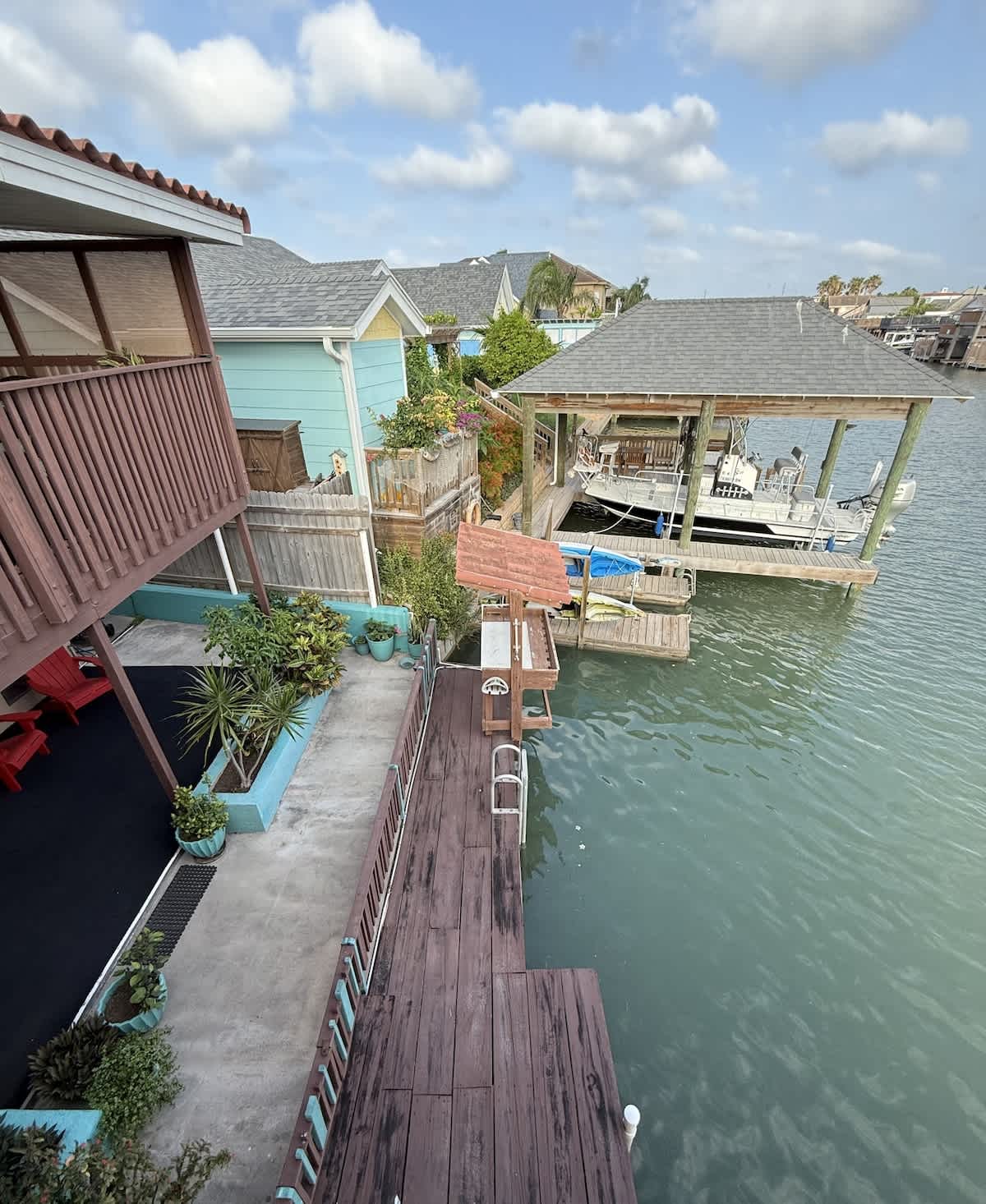 An elevated view of the property's exterior, highlighting the multi-level decks, the boat slip with a boat, and the canal lined with other houses and docks.