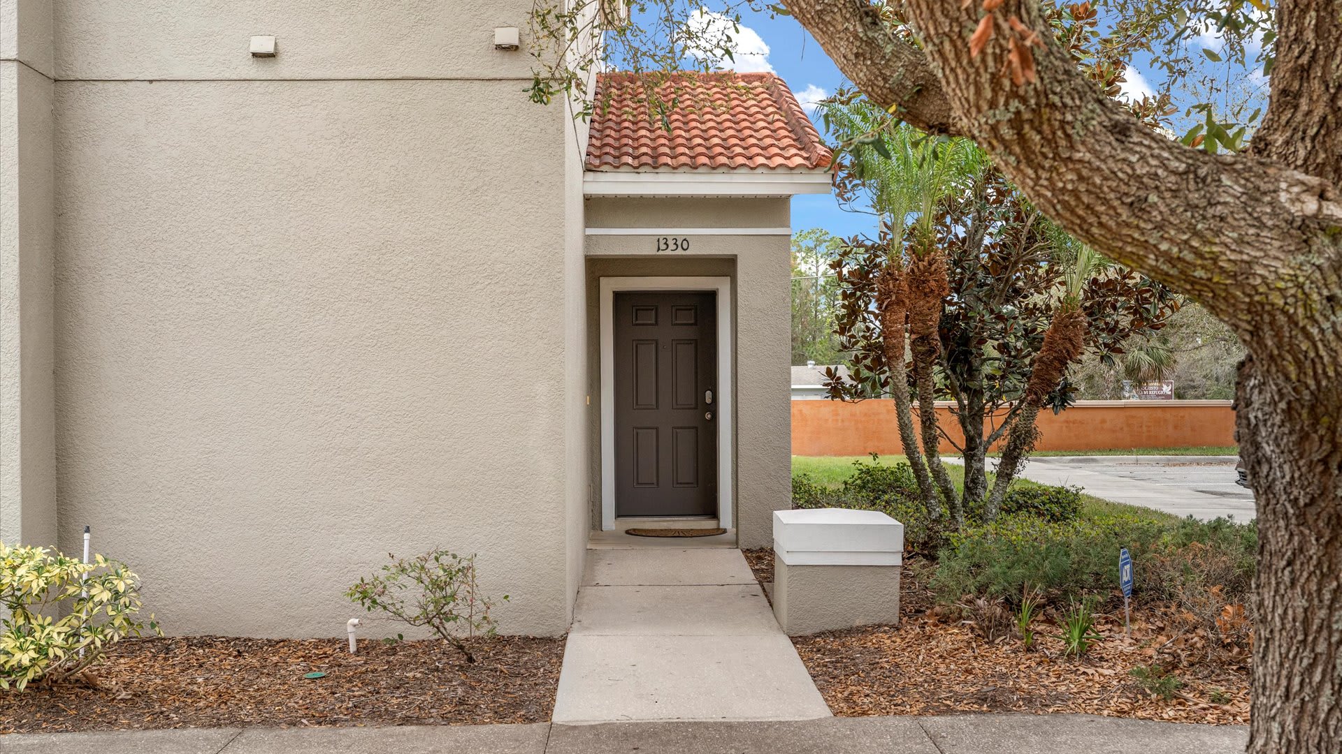 A close-up of the townhouse's front entrance, featuring a dark brown door under a small red tile roof overhang, with the address number 1330 clearly visible.