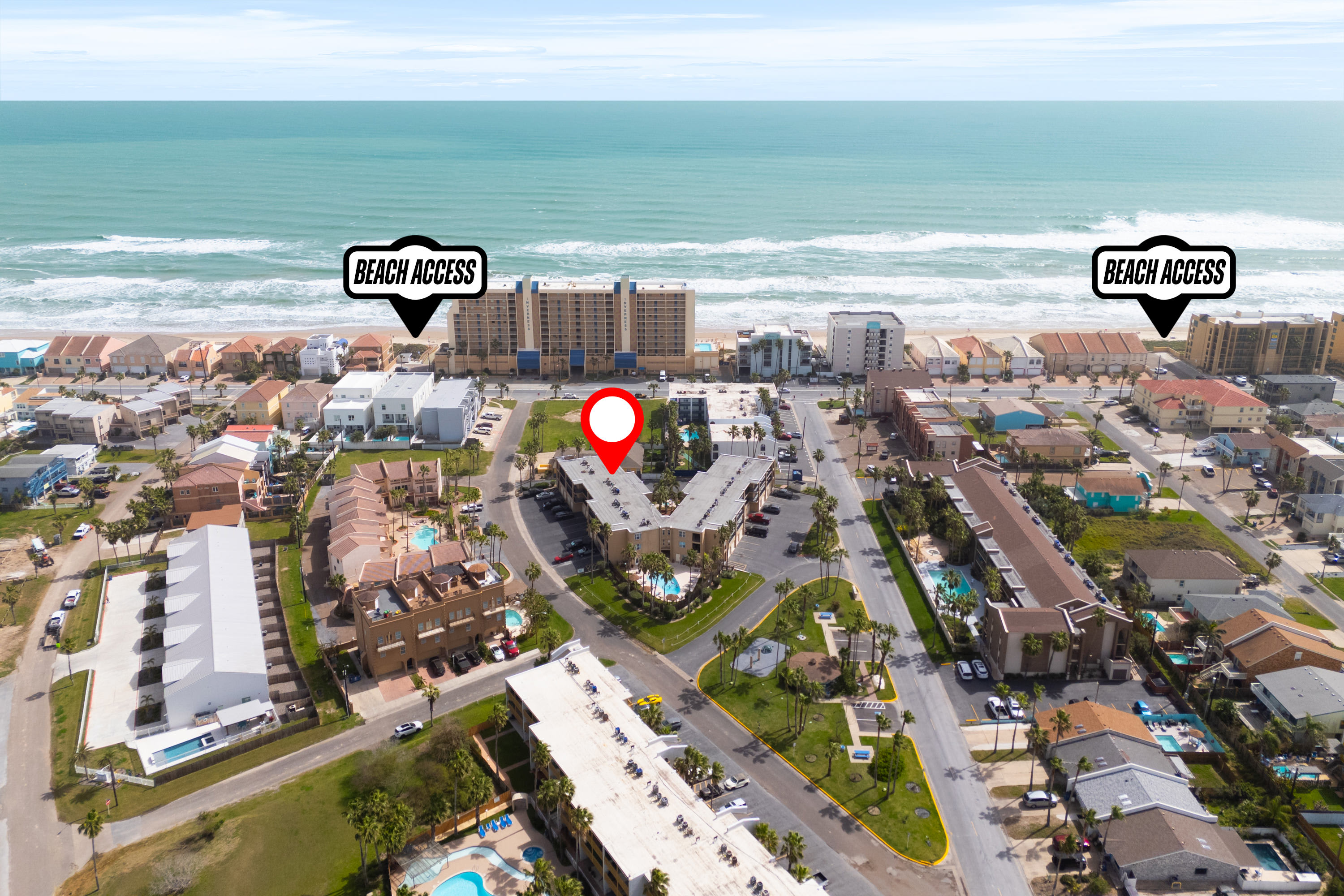 An aerial view of the property and surrounding coastal neighborhood, highlighting its proximity to the beach with "Beach Access" markers. The ocean, residential buildings, and palm trees are visible under a clear sky.