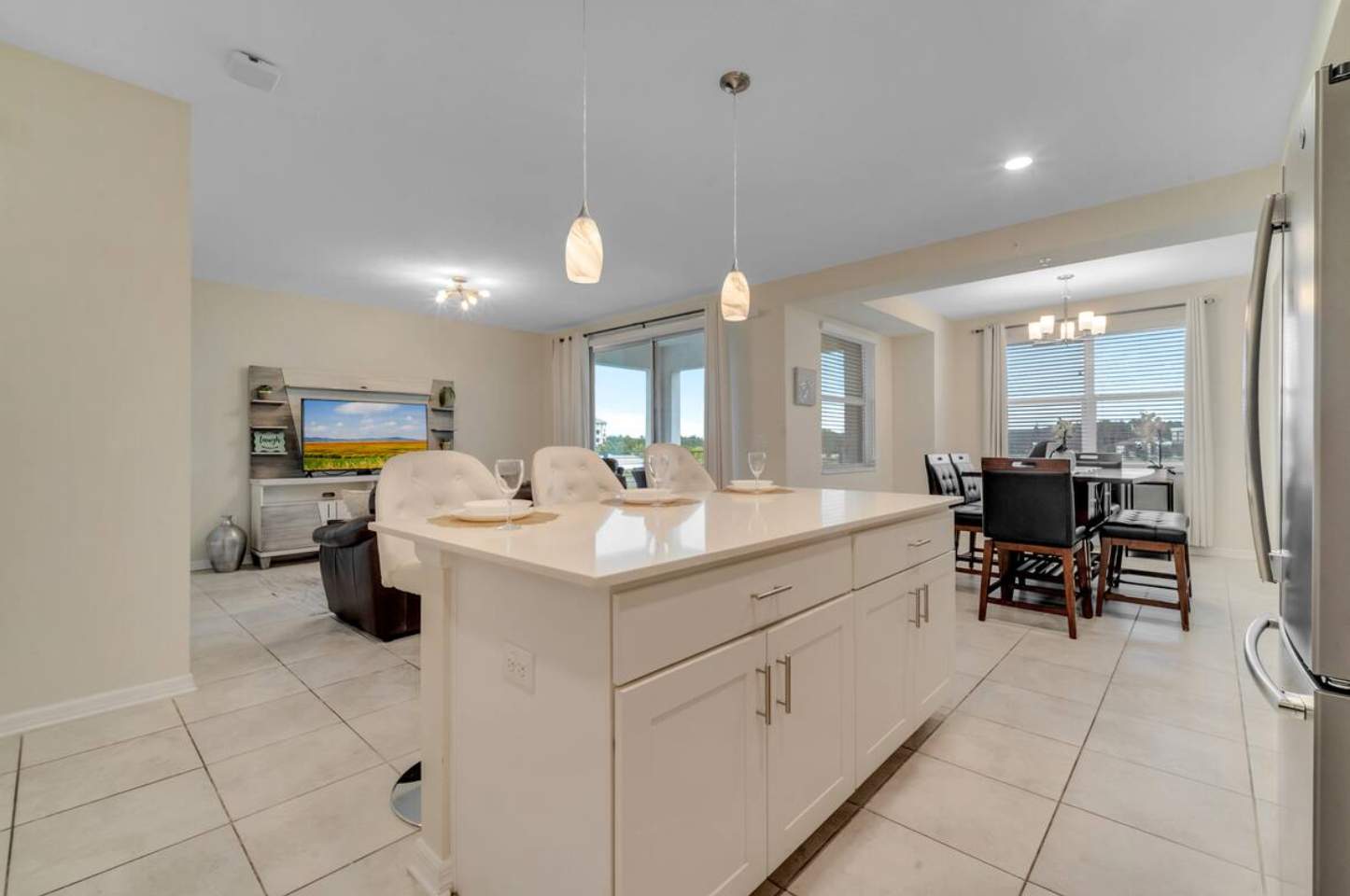 View from the kitchen island looking into the open-concept living and dining areas. The kitchen features white cabinets and a light countertop, with a dining table and living room visible beyond.