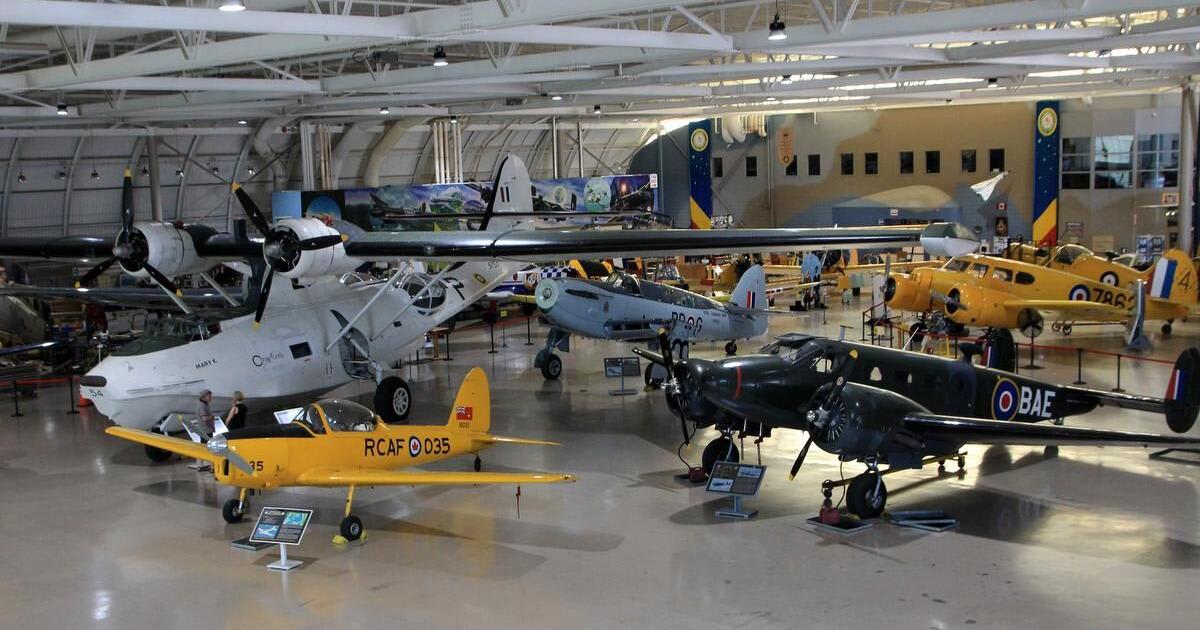 Large indoor museum hangar filled with various vintage aircraft, including biplanes, seaplanes, and propeller planes, displayed on a concrete floor.