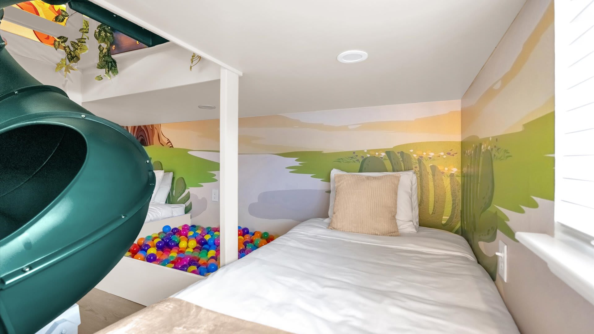 Close-up view inside the themed kids' bunk bed area, revealing a colorful ball pit and a single bed with a beige pillow. Jungle-themed murals continue on the walls, creating an immersive play space.
