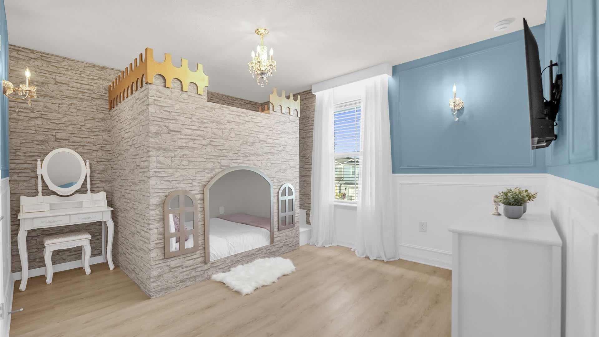 Princess-themed kids' bedroom featuring a large castle-shaped bunk bed structure with a bed nestled inside. A white vanity with a mirror and a chandelier add to the regal decor, set against light wood floors.