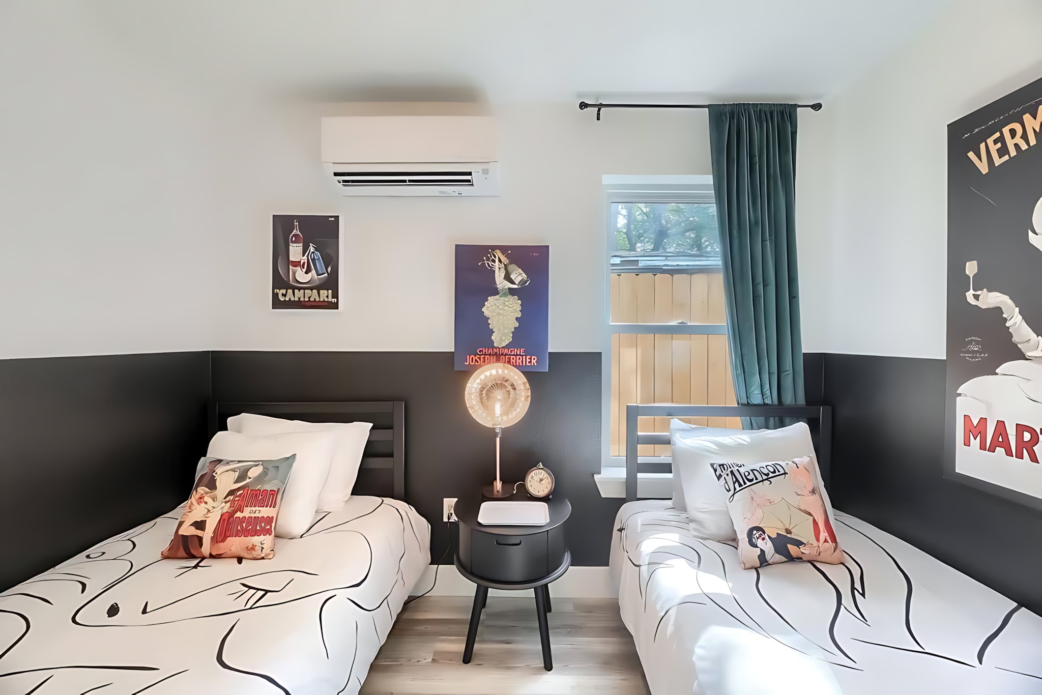 Another perspective of the twin bedroom, showcasing the two beds with graphic pillows, the dark gray wainscoting, and the collection of vintage-inspired wall art.