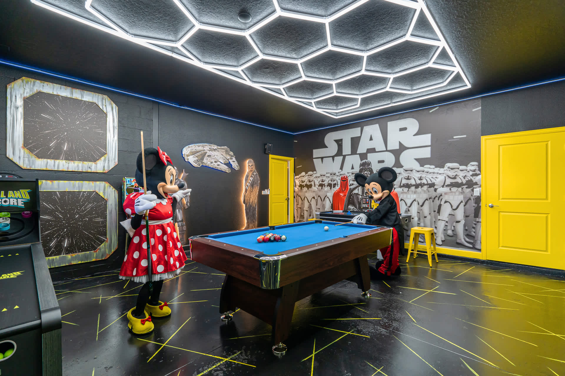 Star Wars-themed game room with Mickey and Minnie Mouse figures playing pool. The room features black walls with Star Wars murals, a pool table, and a hexagonal LED ceiling light fixture.