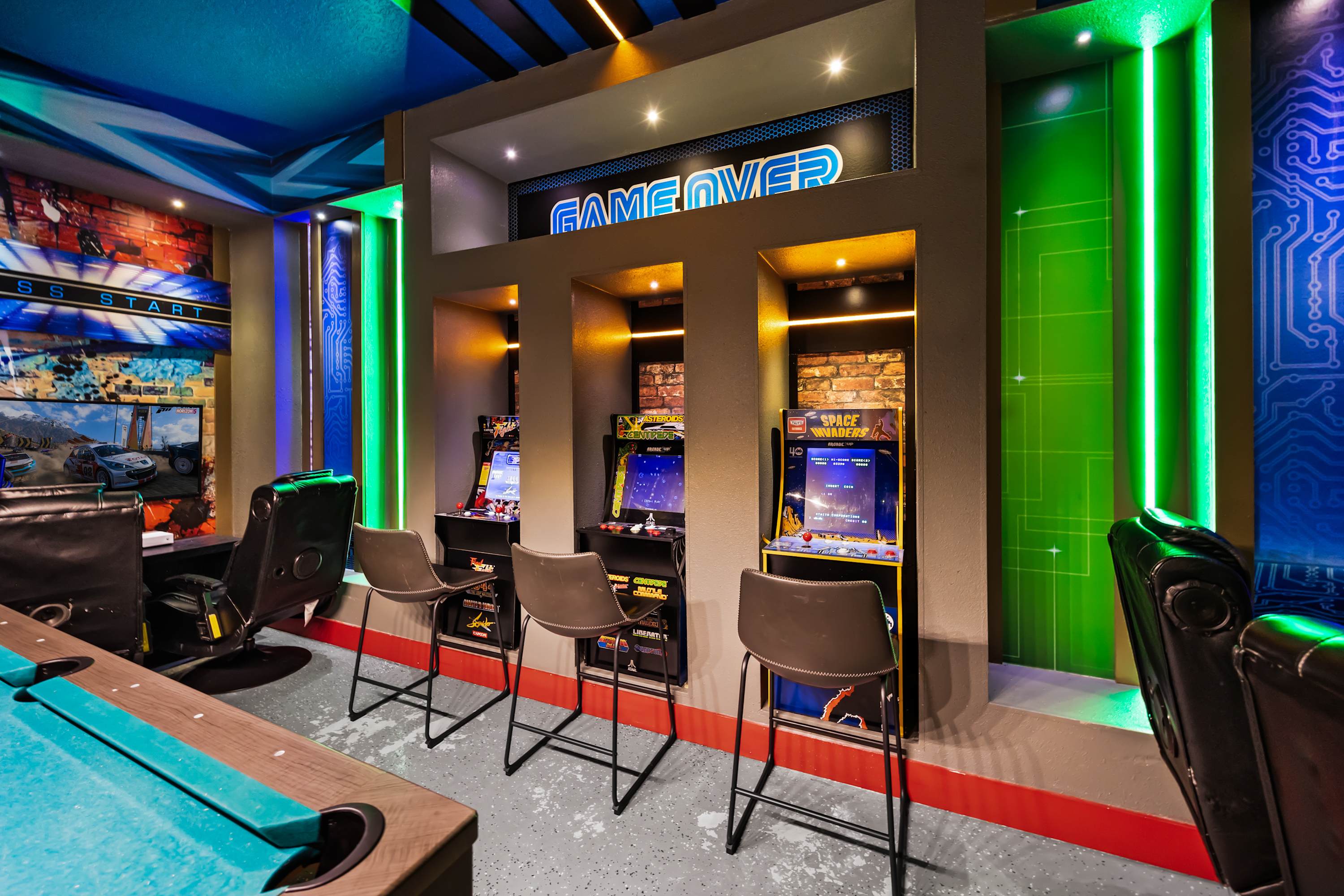 A close-up view of the game room highlights three classic arcade machines set into illuminated alcoves, with "GAME OVER" signage above. Neon green vertical light strips and brick-patterned wallpaper add to the retro-futuristic ambiance.