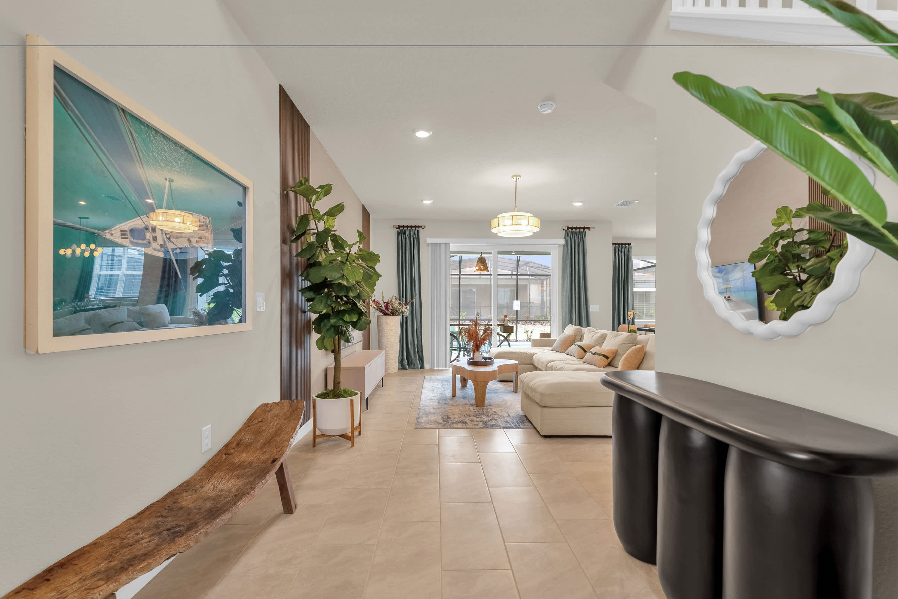 A bright entryway with light tile flooring, leading into an open-concept living space. A long wooden bench and a large framed artwork adorn the left wall, while a decorative mirror and a tall plant are visible on the right.