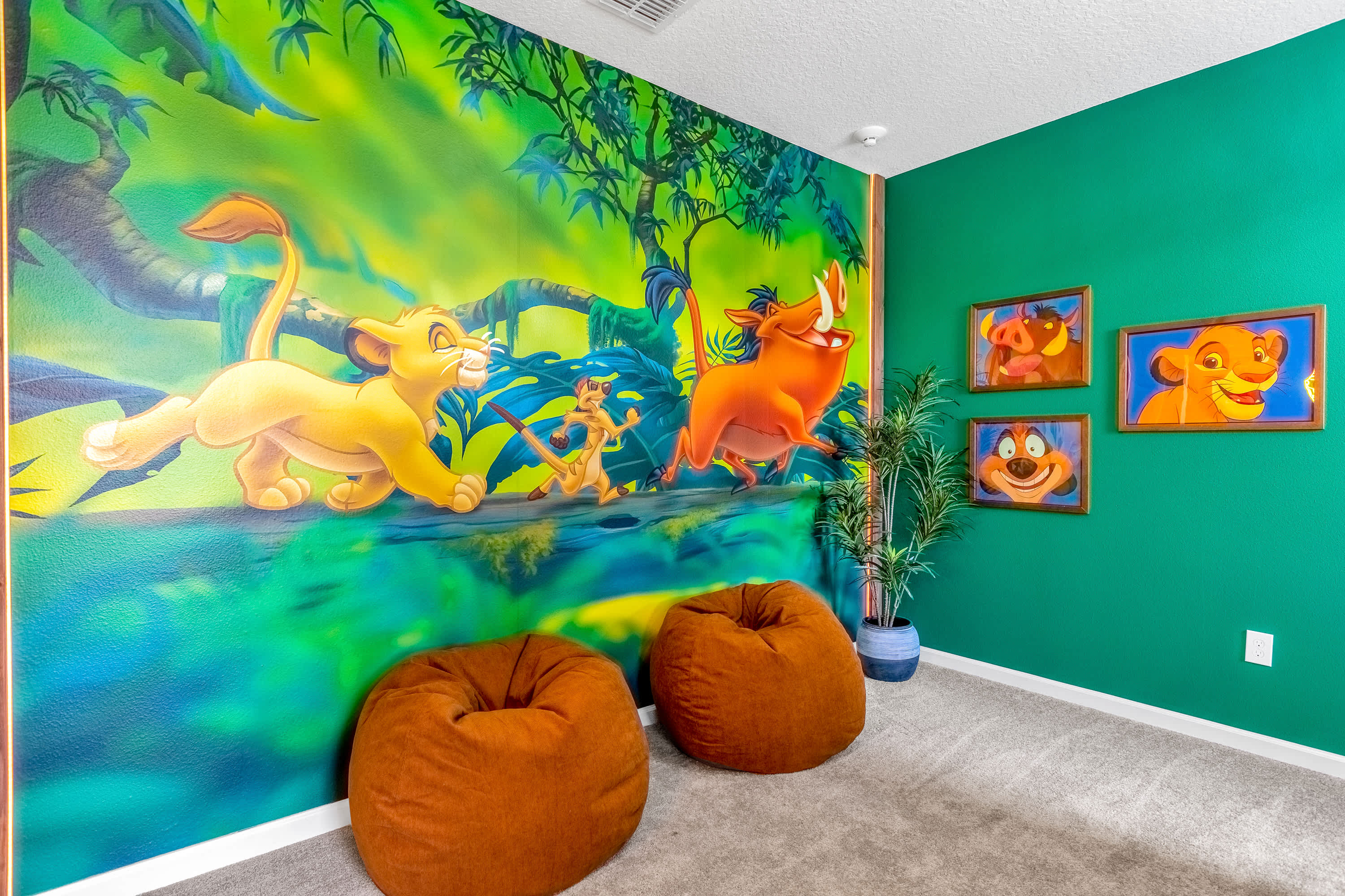 A vibrant "Lion King" themed bedroom showcasing a colorful mural of characters on one wall, bright green walls, and two comfortable orange bean bag chairs on a carpeted floor.