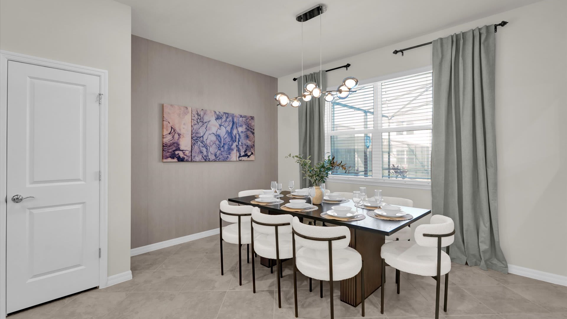 Elegant dining room with a dark rectangular table and eight white upholstered chairs, set against a textured accent wall. A modern linear chandelier hangs above, and large windows with blinds and drapes overlook the exterior.