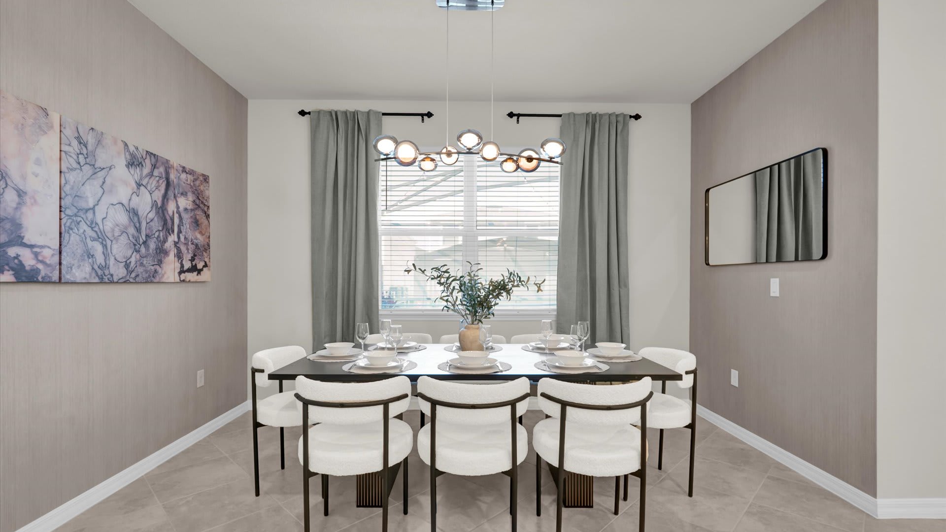 Modern dining room with a long dark wood table set for eight, featuring white upholstered chairs and a contemporary linear chandelier. The walls are covered in a subtle textured wallpaper, and a large abstract artwork hangs on one wall.