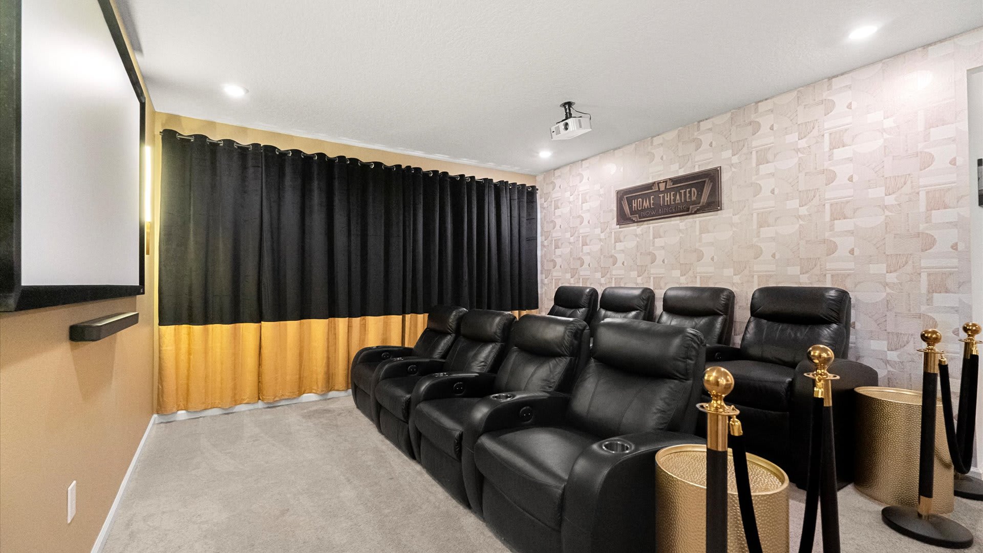 A dedicated home theater room features multiple rows of black leather reclining seats, a large projection screen, and black and gold curtains. The walls are adorned with patterned wallpaper and a 'Home Theater' sign.