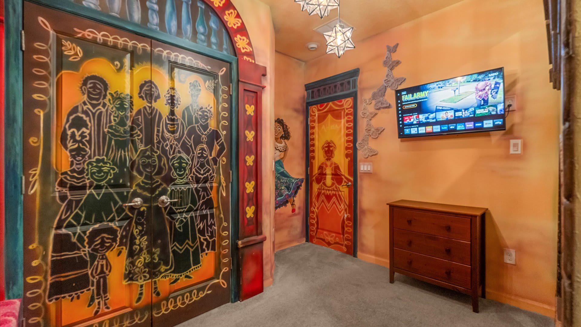 Detailed view of the themed bedroom showcasing two intricately painted doors with colorful character murals, a wooden dresser, and butterfly wall decals. Star-shaped pendant lights hang from the ceiling.
