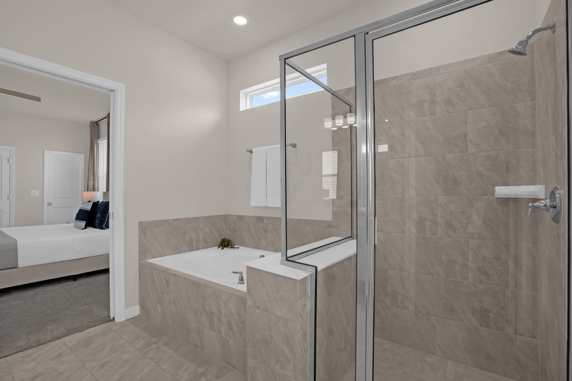 Modern bathroom with a large walk-in shower featuring glass doors and light gray tiles, and a separate built-in bathtub with matching tile surround.