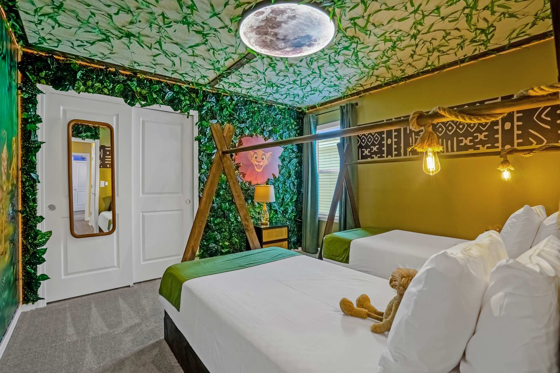 Themed bedroom with two twin beds, a wall covered in artificial vines, a closet with white bi-fold doors, and a full-length mirror reflecting the room.