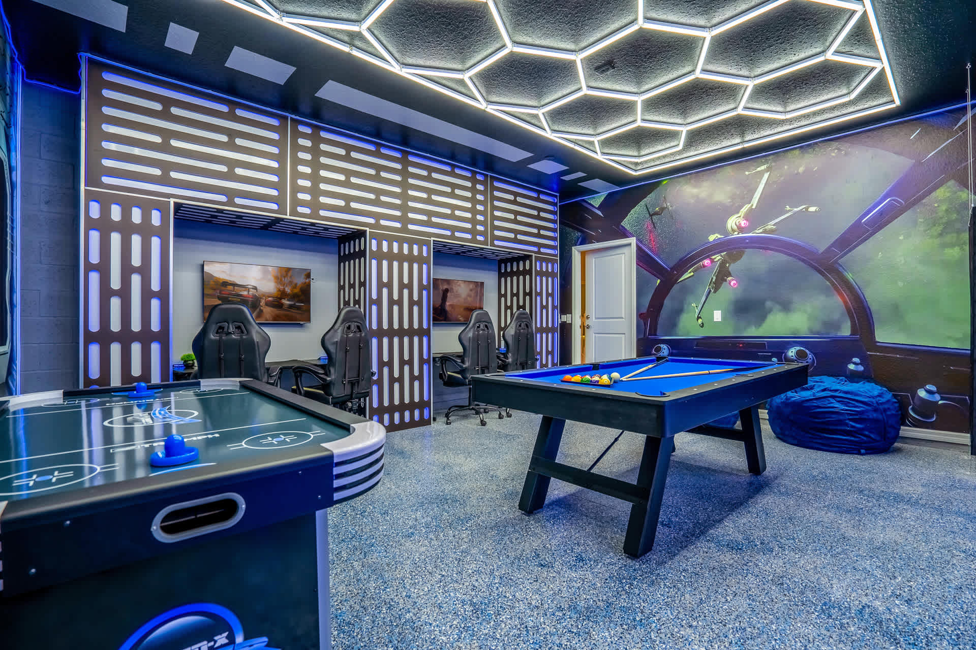 Star Wars-themed game room featuring a pool table, air hockey table, and multiple gaming stations with ergonomic chairs, all under a hexagonal LED-lit ceiling and blue ambient lighting.