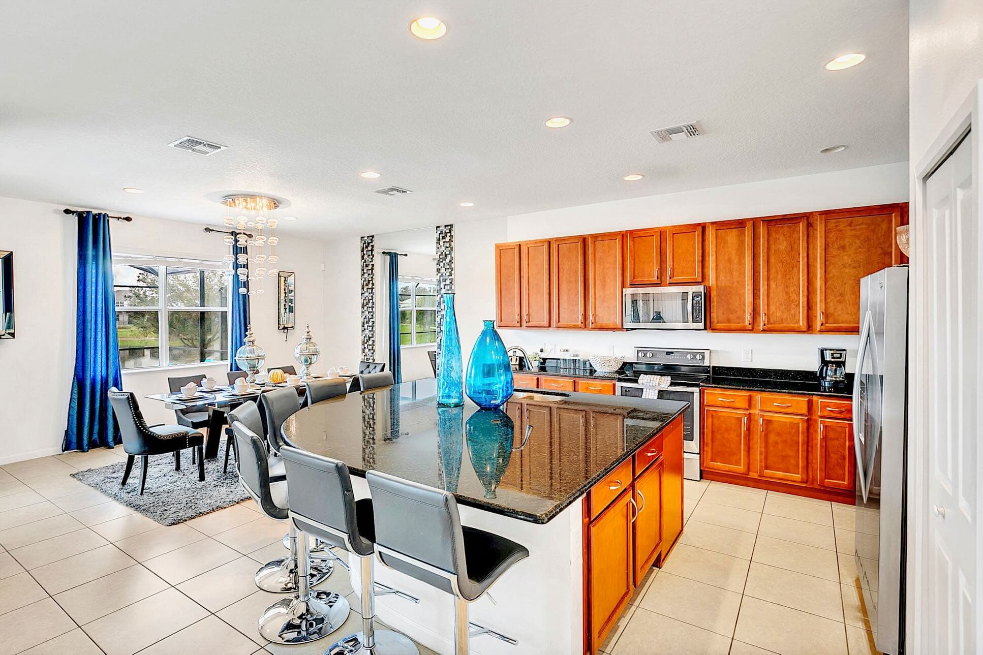 Well-appointed kitchen with warm wooden cabinetry, black granite countertops, and stainless steel appliances, featuring a large island with bar seating, open to the dining area.