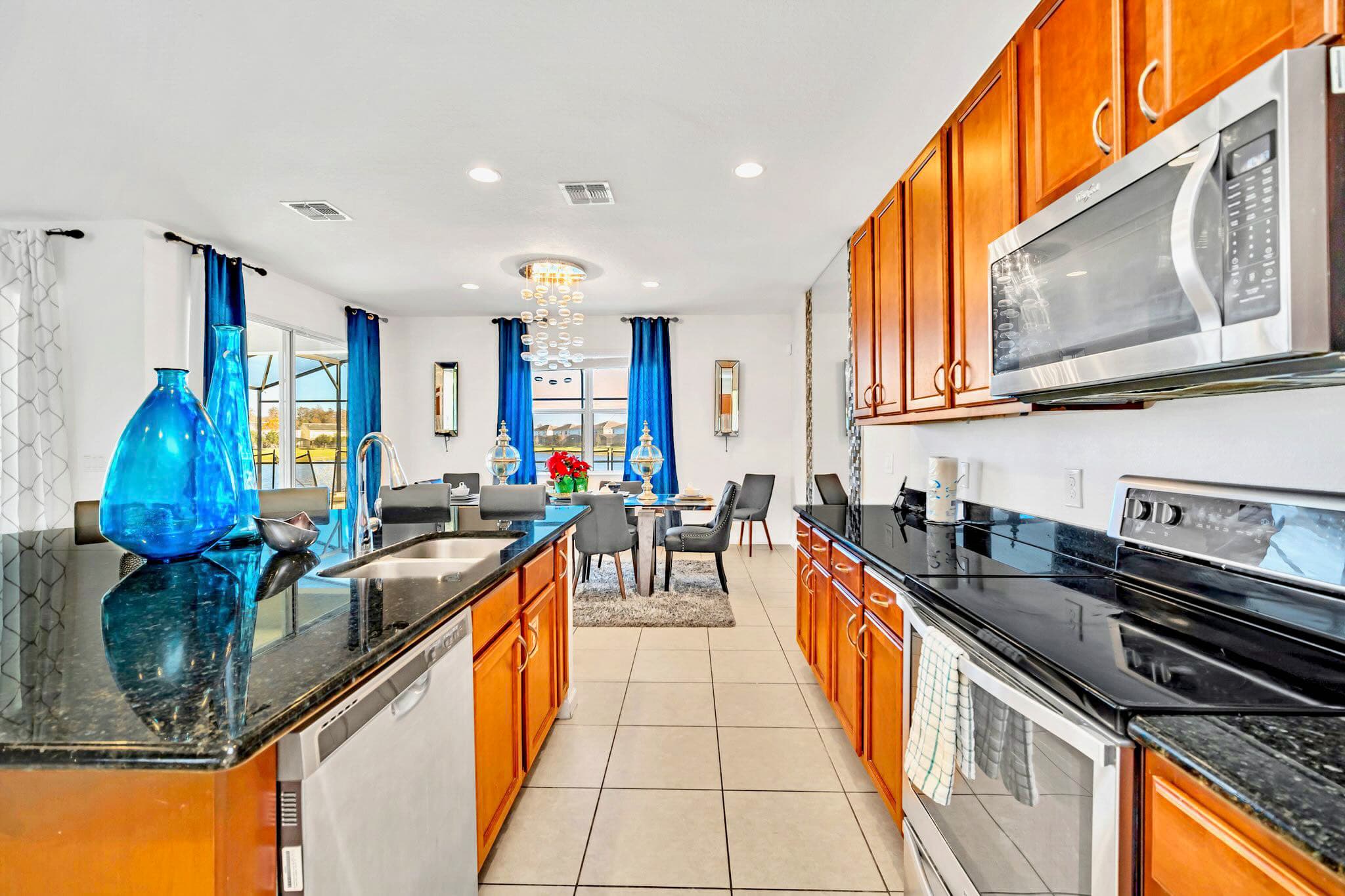 Detailed view of the kitchen showcasing the large island with a double sink and bar seating, surrounded by wooden cabinets, black granite countertops, and stainless steel appliances.