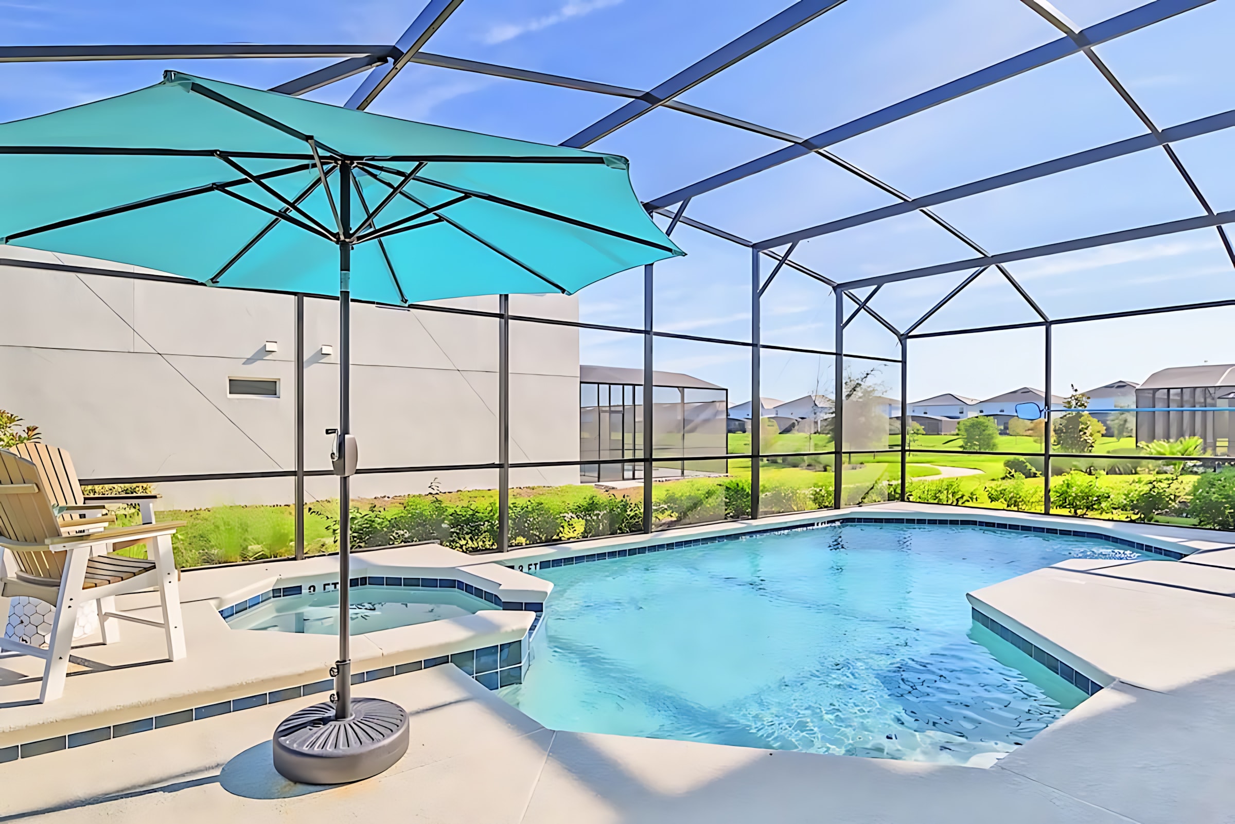 Screened-in private pool area with a rectangular pool and an attached hot tub, featuring a bright turquoise umbrella and two wooden Adirondack chairs on the surrounding patio. The enclosure allows views of the sunny sky and distant houses.