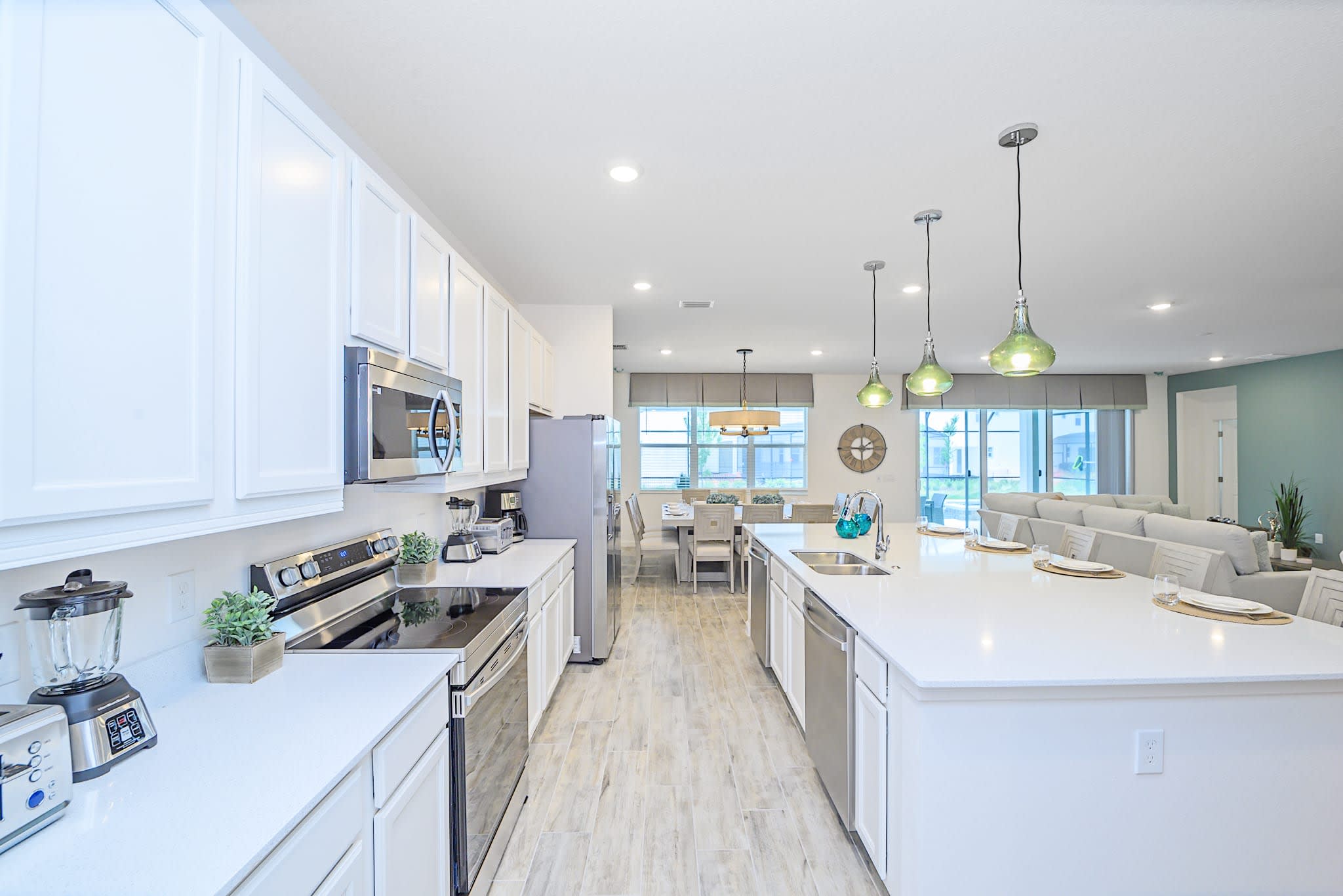 Well-equipped kitchen with white shaker cabinets, stainless steel appliances including a range with an overhead microwave, and ample counter space. A coffee maker and blender are visible, ready for use.