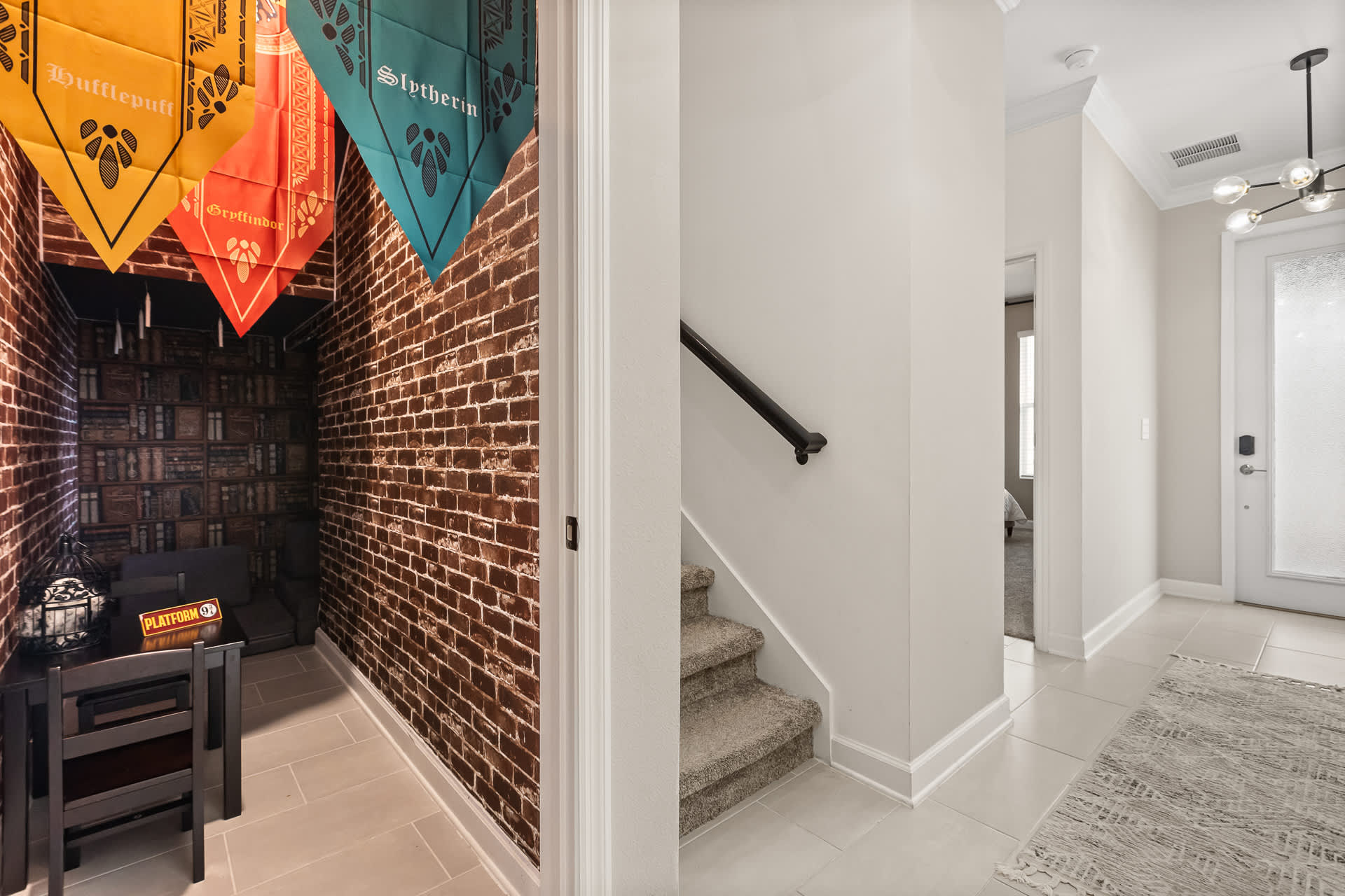 A Harry Potter-themed nook featuring brick-patterned wallpaper, house banners (Hufflepuff, Gryffindor, Slytherin) hanging from the ceiling, and a small table with chairs. A "Platform 9 3/4" sign is visible, creating an immersive magical atmosphere.