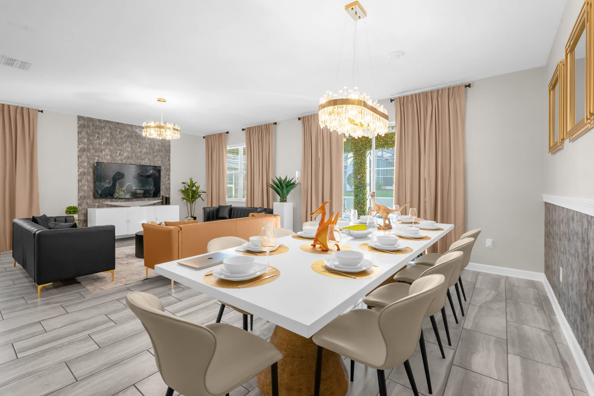 A bright dining area features a long white table set for eight with beige chairs, adorned with dinosaur figurines, and is open to the living room with its modern sofas.
