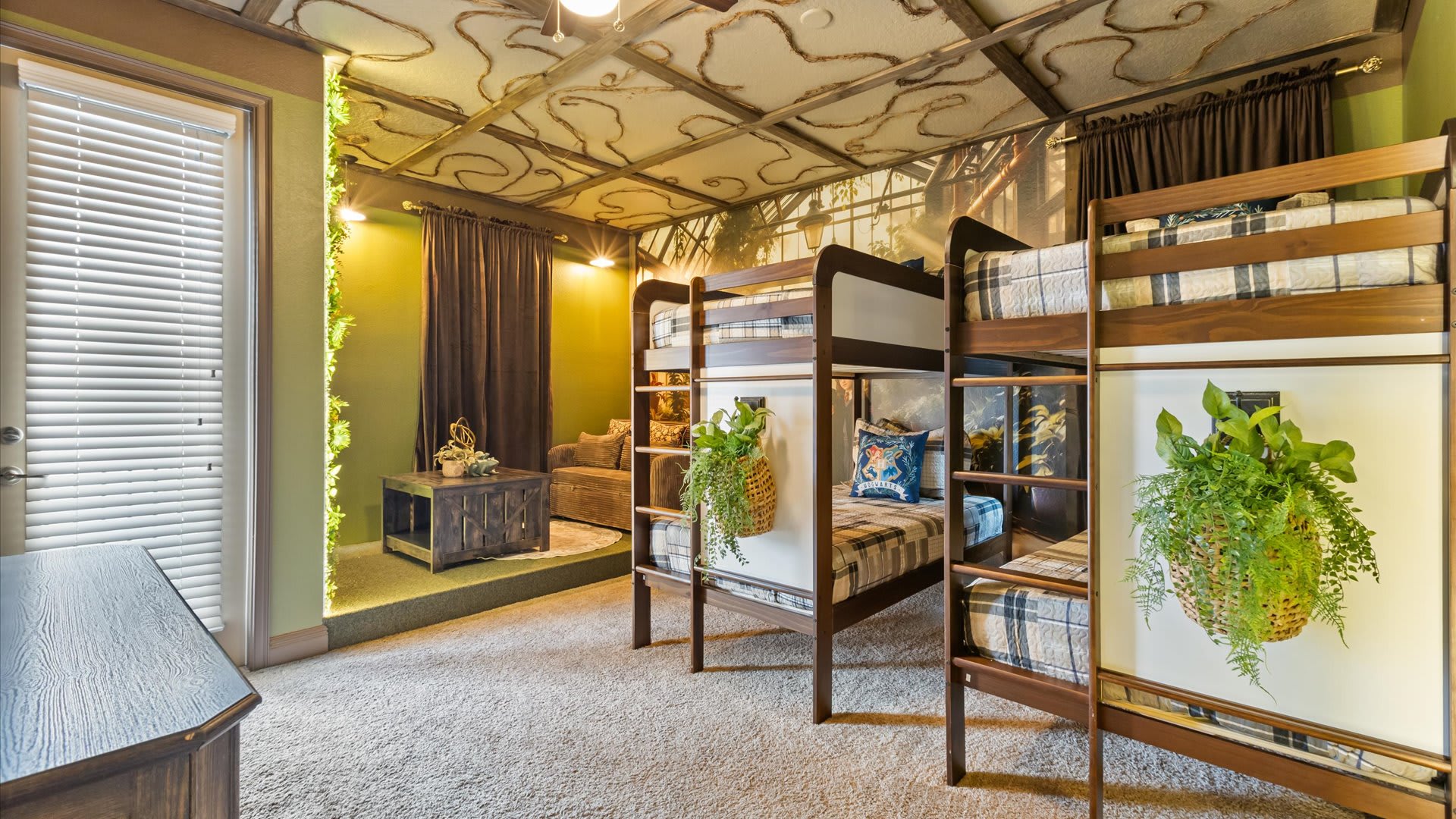 A wide view of the themed bedroom showcasing two sets of wooden bunk beds with plaid bedding, a cozy seating area with a pull-out sofa, and a door leading to an outdoor space.