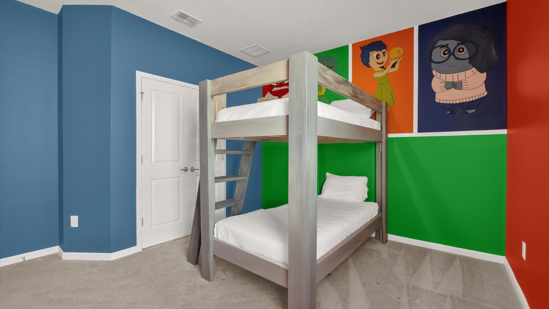 Vibrantly themed kids' bedroom featuring a wooden bunk bed with white bedding. The walls are painted in bold blue, green, and red, adorned with colorful character murals.
