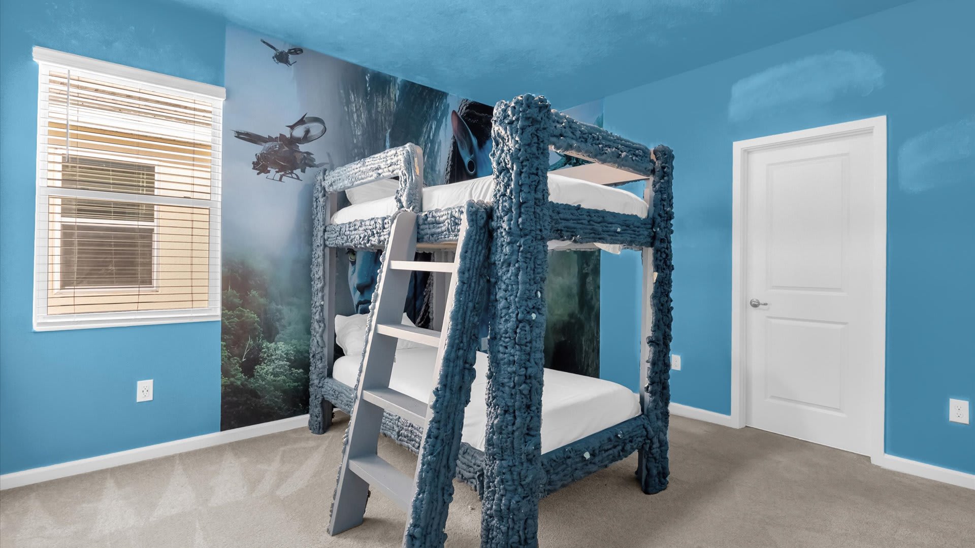 Avatar-themed bedroom featuring a unique blue textured bunk bed and a large mural on the wall depicting scenes from the movie. The room has blue walls and a carpeted floor.
