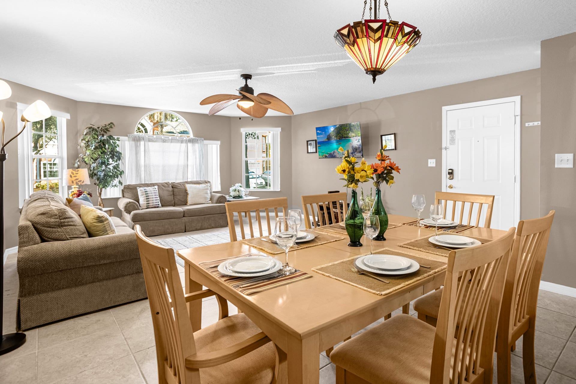 A view of the dining area from a different angle, showing the wooden dining table and chairs, with the living room and front door visible in the background.