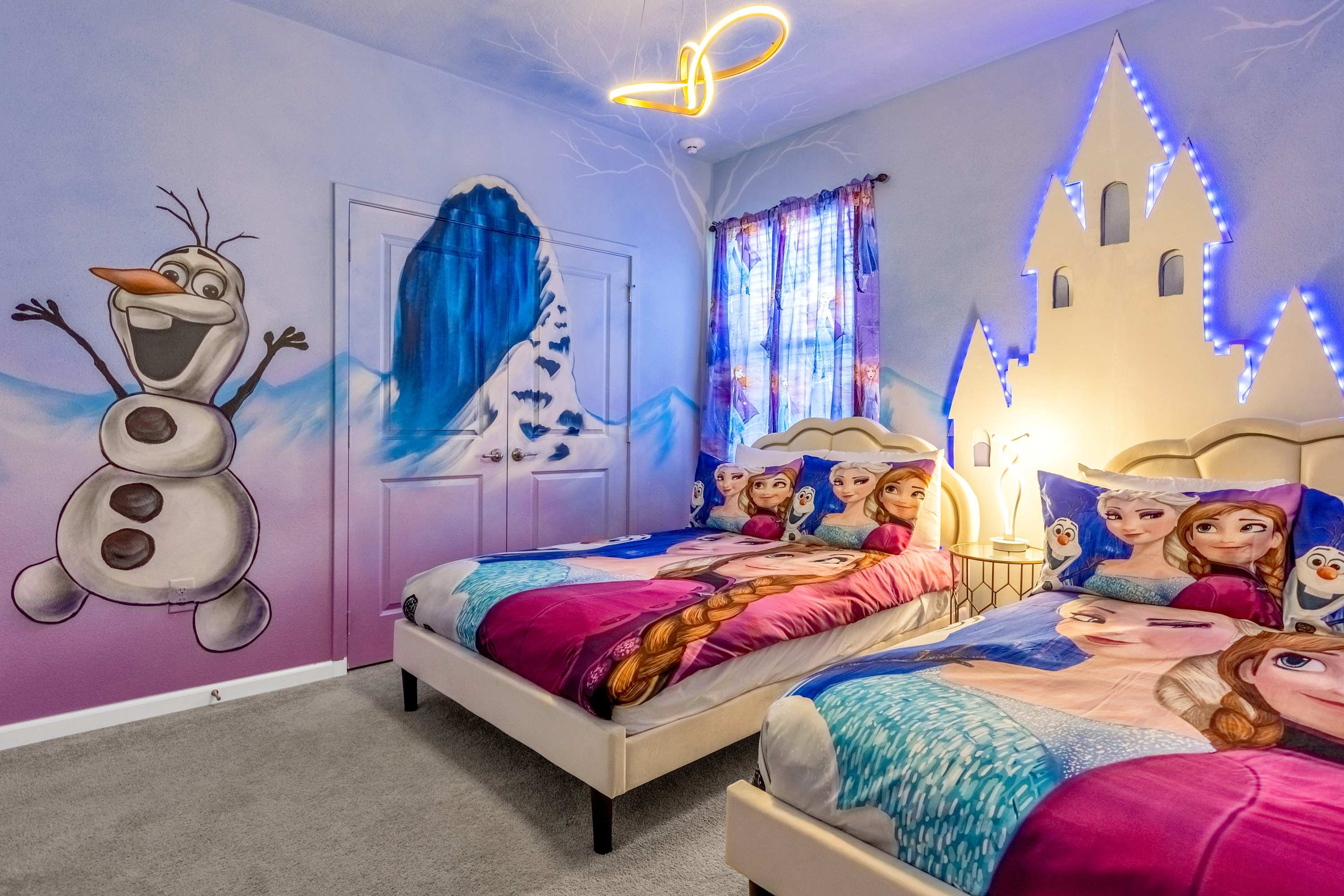 A vibrant Frozen-themed bedroom with two single beds featuring character bedding, a large Olaf mural on a purple and blue gradient wall, and a white castle headboard with blue LED lighting.
