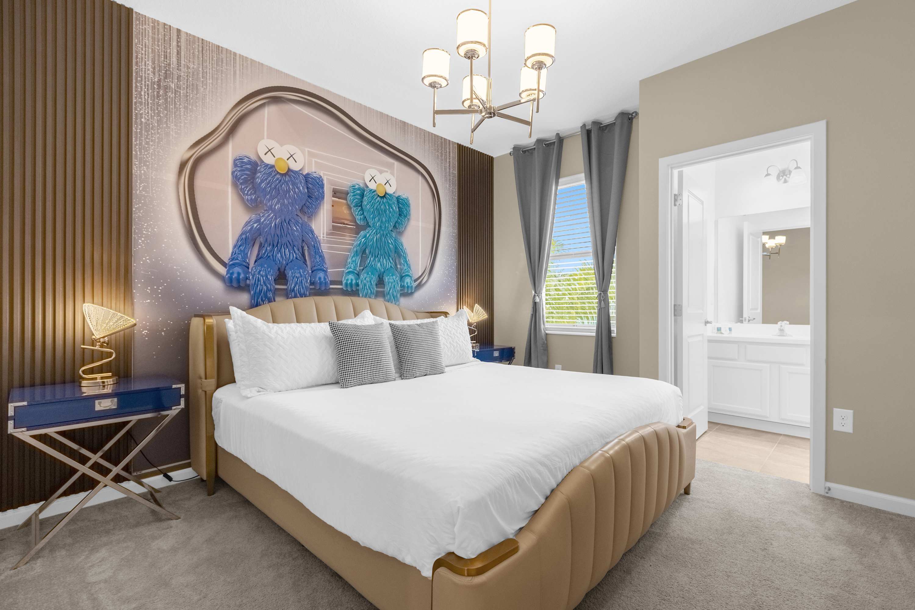 Contemporary bedroom with a king-sized bed, a striking accent wall featuring large blue and teal KAWS-style figures, and a window with grey curtains, lit by a modern chandelier.