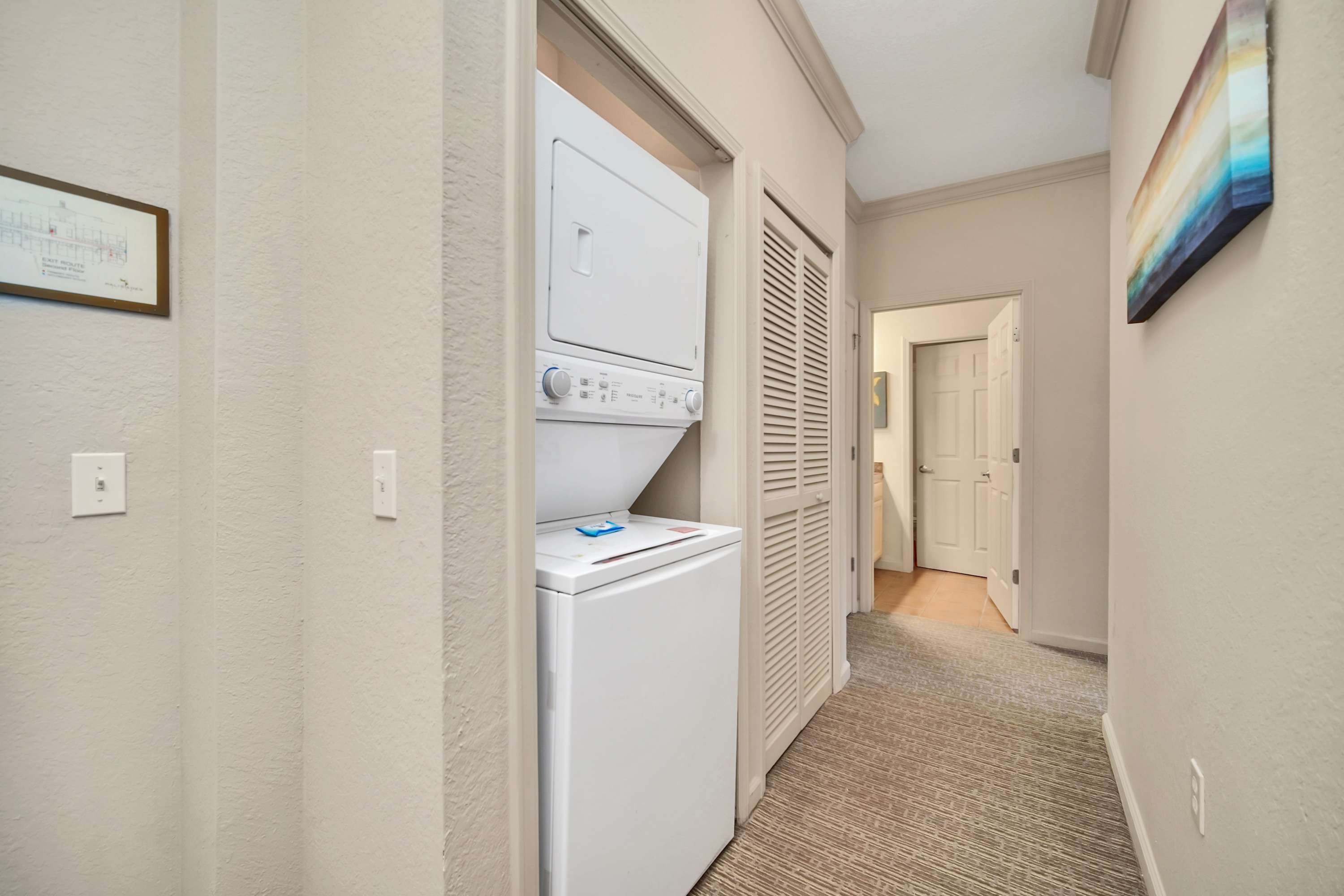 Hallway laundry closet with a stacked white washer and dryer unit, providing convenient in-unit laundry facilities.